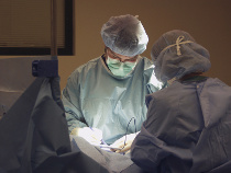 Surgeon making incision during surgery with scrub nurse assisting